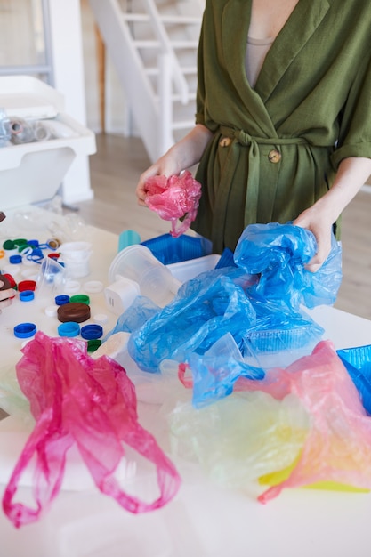 Портрет современной женщины в среднем разделе, сортирующей пластиковые отходы дома перед переработкой