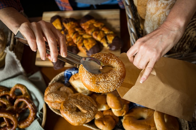 Mid section of staff packing doughnut in paper bag at counter