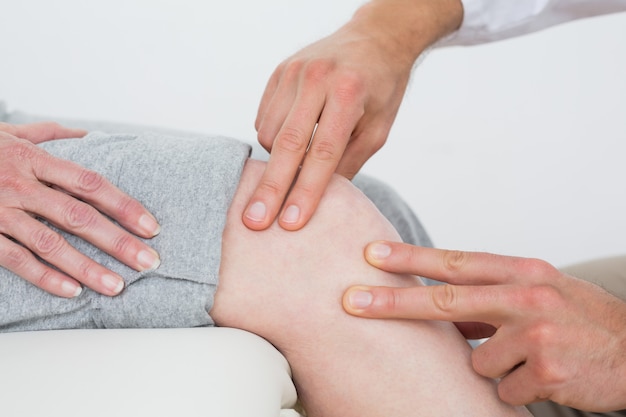 Mid section of a woman getting her knee examined