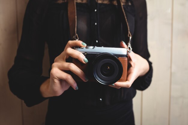 Mid-section of woman standing with camera