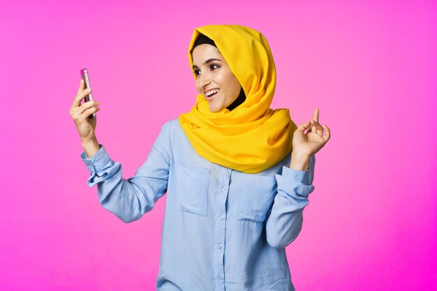 Mid section of woman using smart phone against pink background