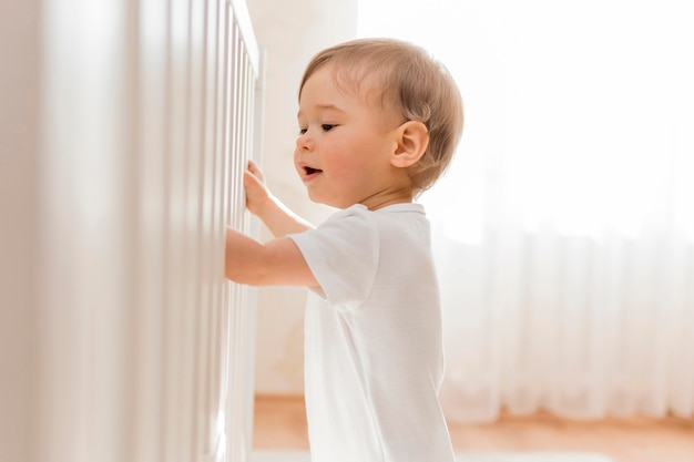 写真 ベビーベッドの近くの半ばショットの赤ちゃん