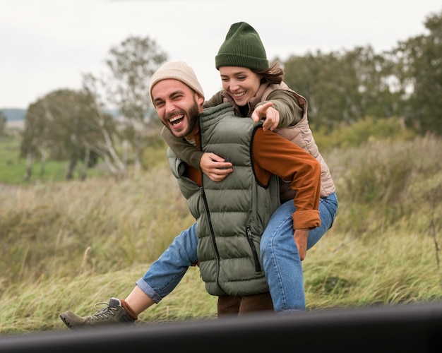 Mid shot man giving piggyback ride to woman