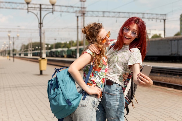 Foto donne a metà tiro che prendono selfie nella stazione ferroviaria