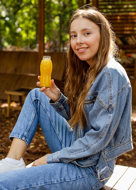 Foto donna giovane del colpo metà che tiene la bottiglia del succo fresco