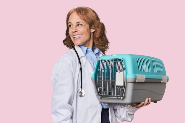 Photo midaged caucasian vet with carrier looks aside smiling cheerful and pleasant