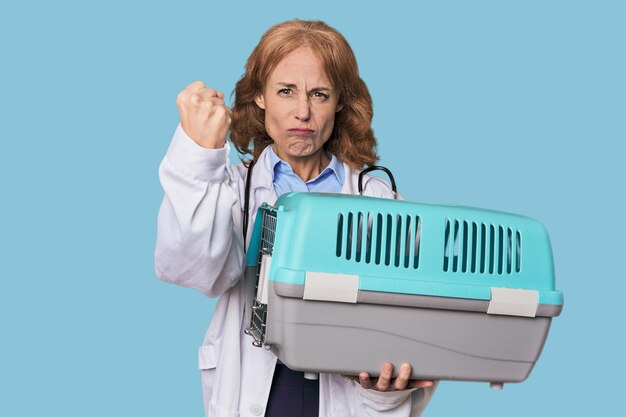 Midaged Caucasian vet with carrier showing fist to camera aggressive facial expression
