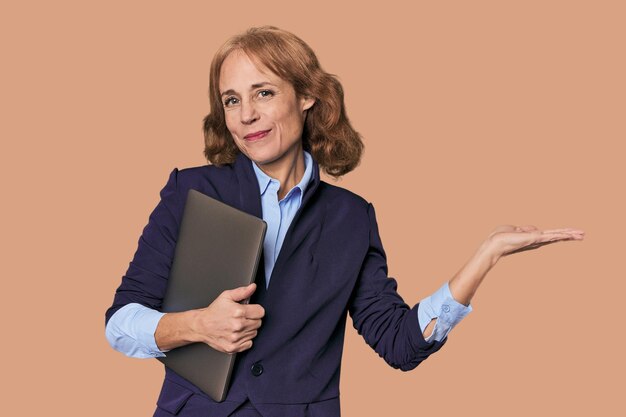 Photo midaged caucasian with laptop in studio showing a copy space on a palm and holding another hand