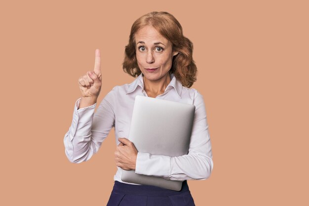 Midaged Caucasian with laptop in studio showing number one with finger