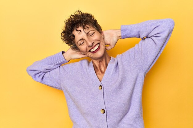 Photo midaged caucasian woman on vibrant yellow stretching arms relaxed position