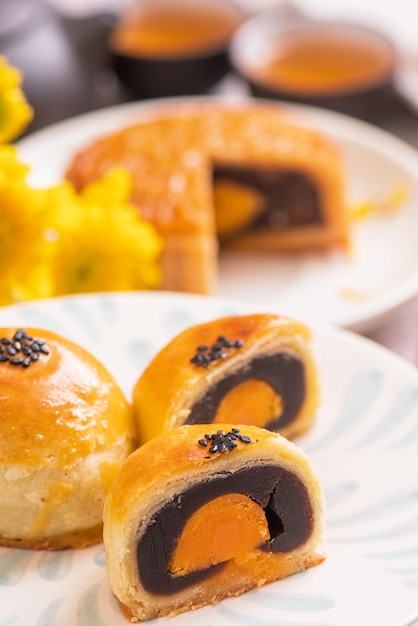 Midautumn festival traditional food concept beautiful cut moon cake on blue pattern plate on white background with flower close up copy space