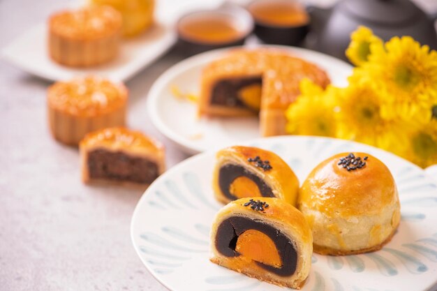 MidAutumn Festival traditional food concept Beautiful cut moon cake on blue pattern plate on white background with flower close up copy space