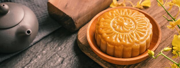 MidAutumn Festival traditional food concept Beautiful Moon cake on black slate table with tea pastry mold flower close up copy space