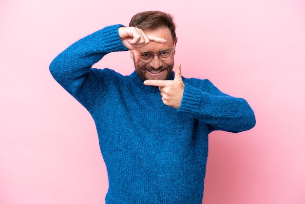 Middelbare leeftijd blanke man geïsoleerd op roze achtergrond scherpstellen gezicht Framing symbool