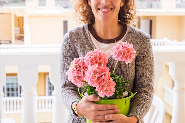 middelbare leeftijd blanke vrouw glimlacht en beschermt haar bloemen.