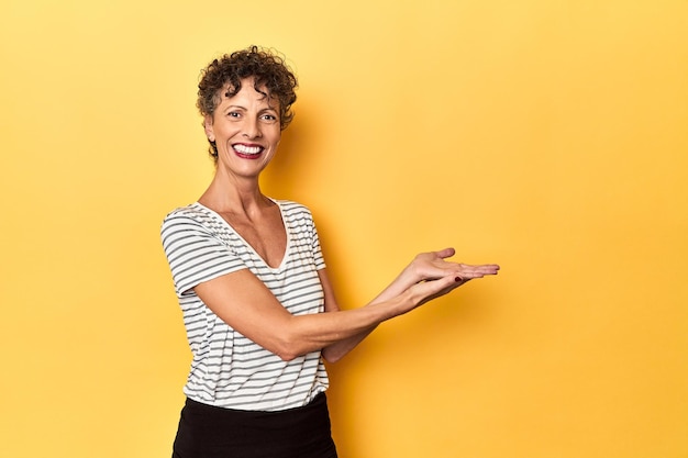 Foto middelbare leeftijd blanke vrouw op levendig geel met een kopieerruimte op een handpalm