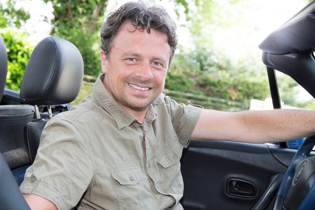 Foto middelbare leeftijd man zit in haar converteerbare auto