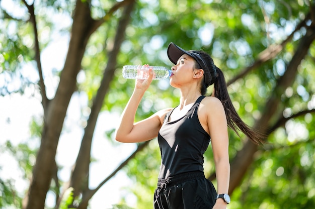 middelbare leeftijd Mooie Sport Aziatische vrouw drinkwater na het joggen, gezond en sport concept.