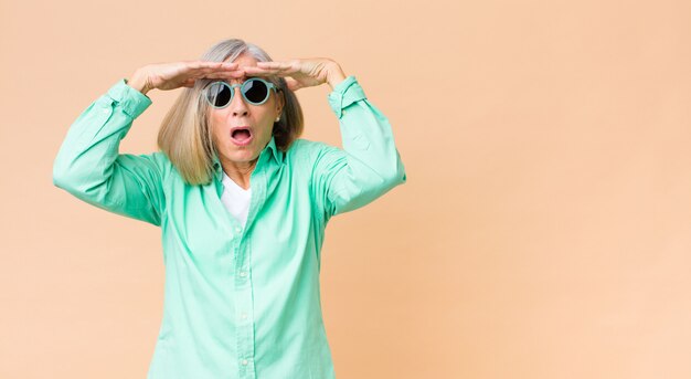 Foto middelbare leeftijd mooie vrouw die zonnebril draagt tegen exemplaar ruimtemuur