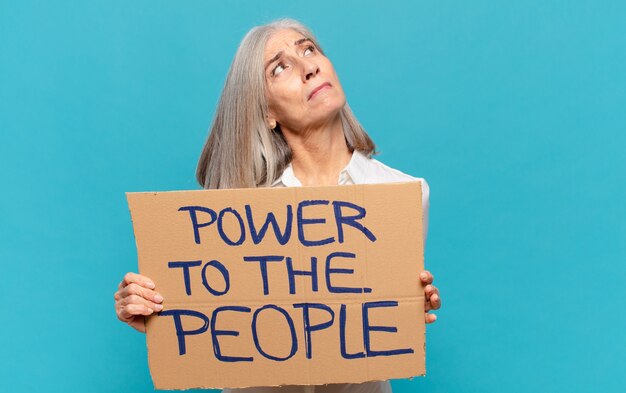 Middelbare leeftijd vrouw met bordje met tekst: Power to the people