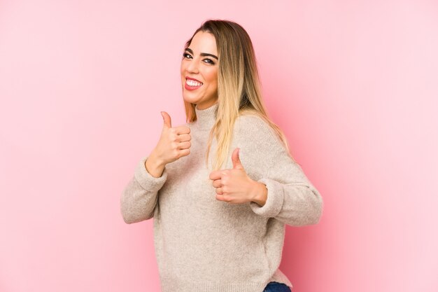 Middelbare leeftijd vrouw over geïsoleerde verhoging van beide duimen omhoog, glimlachend en vol vertrouwen.