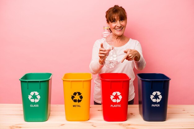 Middelbare leeftijd vrouw recycling geïsoleerd op roze background