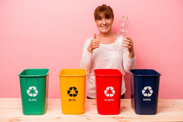 Middelbare leeftijd vrouw recycling geïsoleerd op roze background