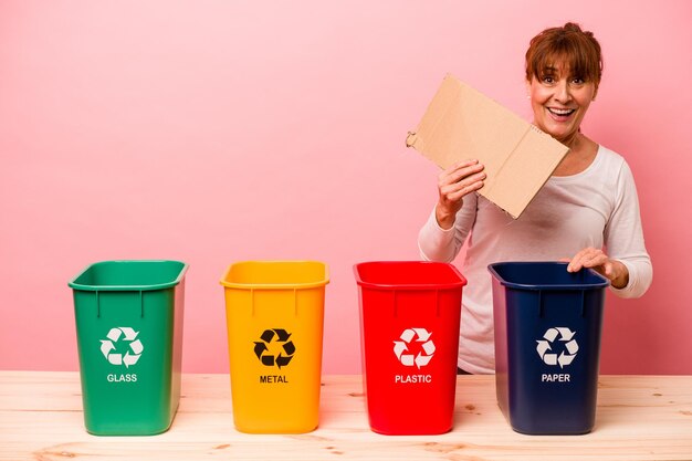 Middelbare leeftijd vrouw recycling geïsoleerd op roze background