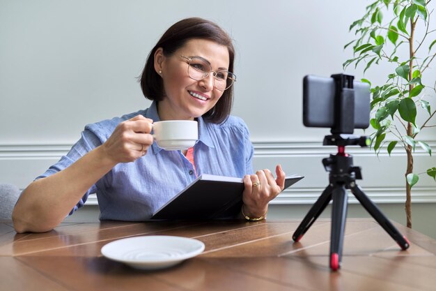 Middelbare leeftijd zakenvrouw counselor mentor in een videovergadering met behulp van een smartphone