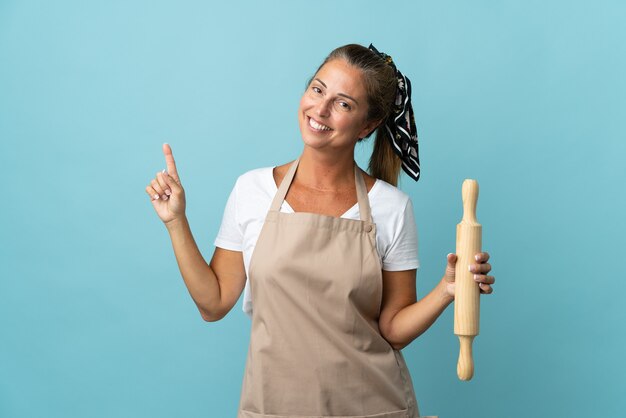 Middelbare leeftijdsvrouw in eenvormige chef-kok die en een vinger in teken van het beste tonen opheft