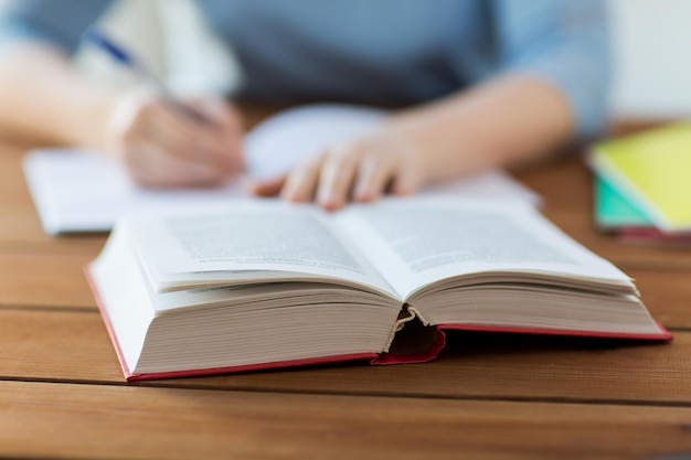 middelbare school, onderwijs, mensen en leerconcept - close-up van een jonge student of vrouw die thuis naar een notitieboekje schrijft