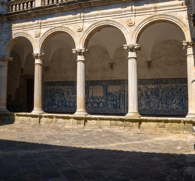 Middeleeuwse geornamenteerde bogen en de blauwe tegelpanelen die de muren van het kathedraalklooster bedekken met de schaduw van het dak op de vloer Kathedraal van Santa Maria Viseu Portugal