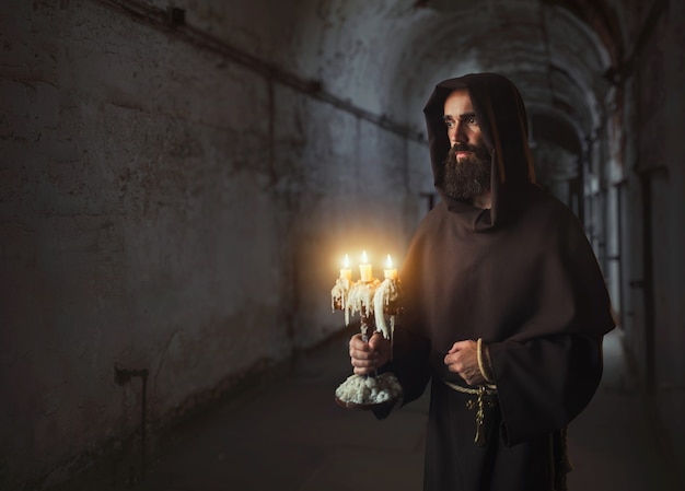 Middeleeuwse monnik in gewaad houdt een kandelaar in handen