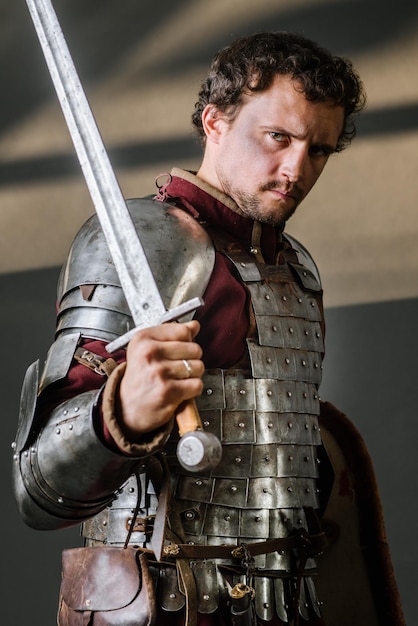 Middeleeuwse ridder in harnas met zwaard en schild op de donkere achtergrond