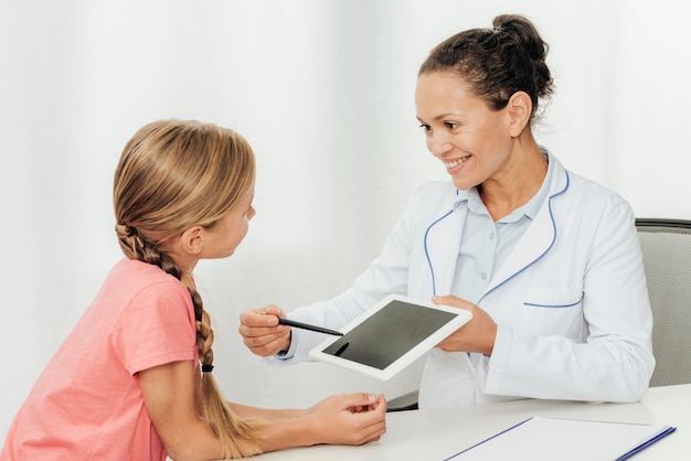 Middelgroot geschoten meisje dat tablet bekijkt