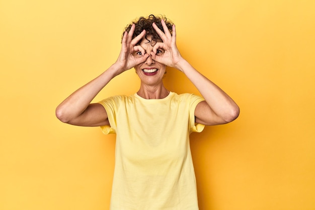 Foto middelgrote blanke vrouw op levendig geel met goed teken over ogen