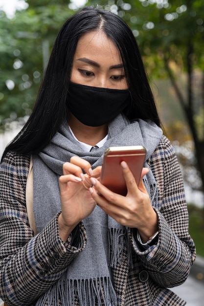 Foto middelgrote geschoten vrouw met masker en telefoon