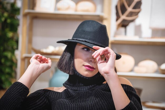 Middelgrote vrouw met een hoed die wegkijkt terwijl ze thuis zit