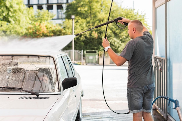 Foto middellange geschoten man wassen auto met slang