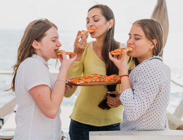 Middellange geschotene meisjesvrienden die pizza eten