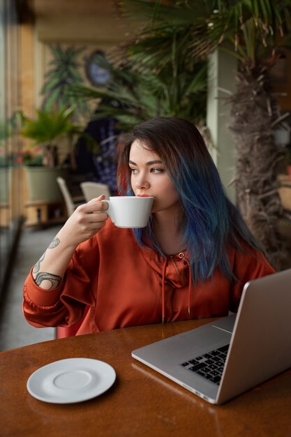 Foto middellange shot jonge vrouw die in de coffeeshop zit