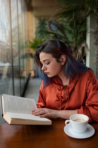 Foto middellange shot jonge vrouw die in de coffeeshop zit