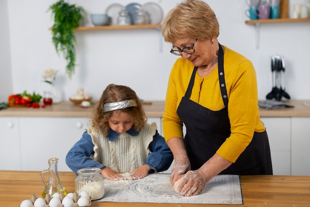 Foto middellange shot oude vrouw en meisje in de keuken