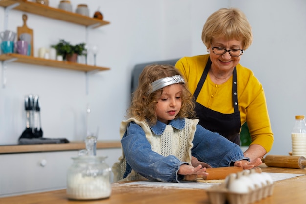 Foto middellange shot oude vrouw en meisje in de keuken