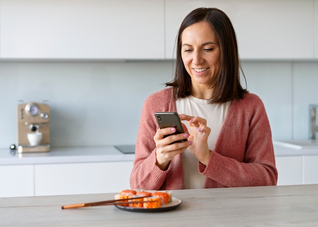 Foto middellange shot vrouw die thuis sushi eet