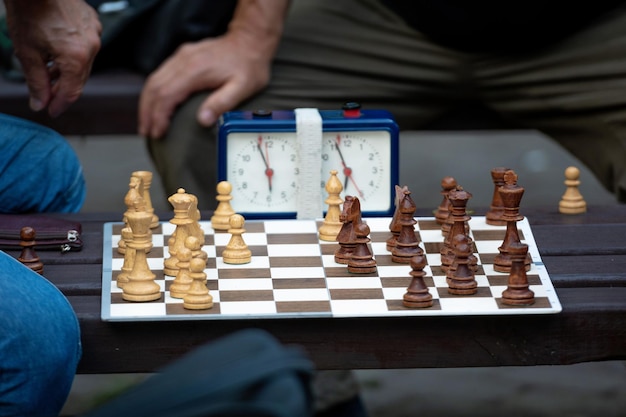 Foto middels sectie van mannen die schaak spelen met de klok op tafel.