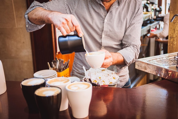 Middelsectie van barista die room in een koffiekop in een café giet