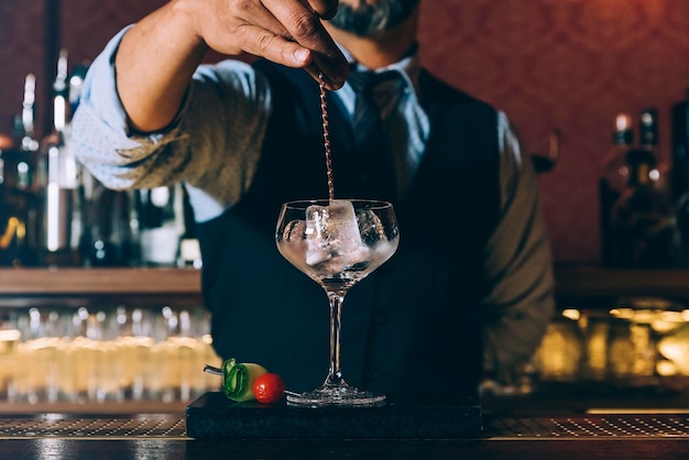 Foto middelsectie van barman die een cocktail bereidt in de bar