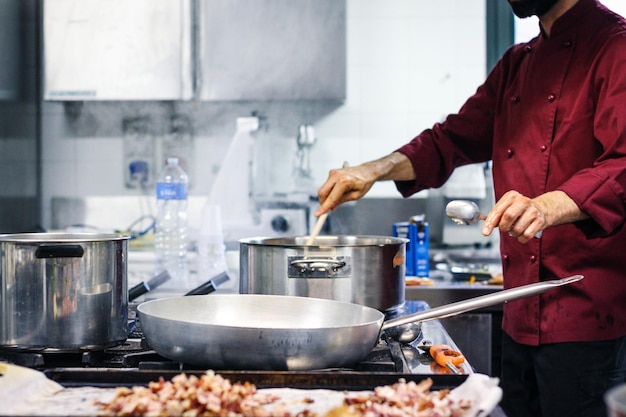 Middelsectie van chef-kok die eten bereidt in de keuken