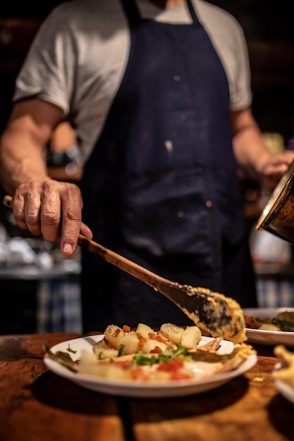Middelsectie van chef-kok die eten op een bord serveert in een restaurant